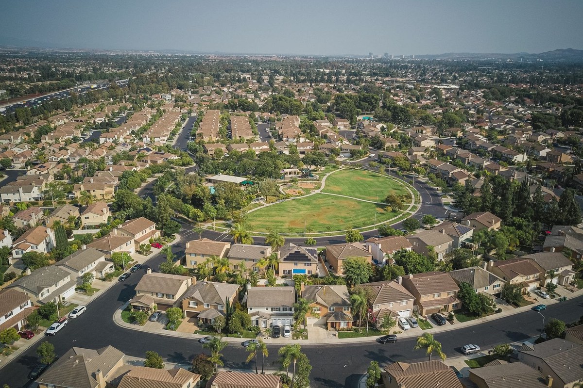 Aerial view of a master-planned suburban neighborhood with curving streets around a central green park.